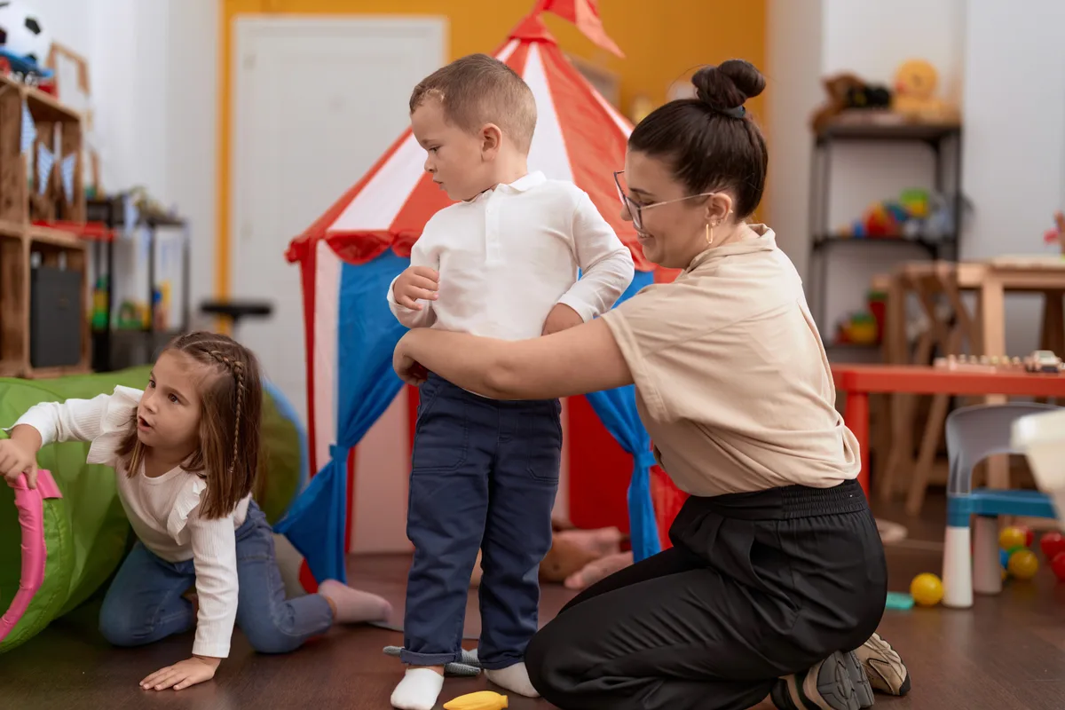 A carer helping a child in a playroom