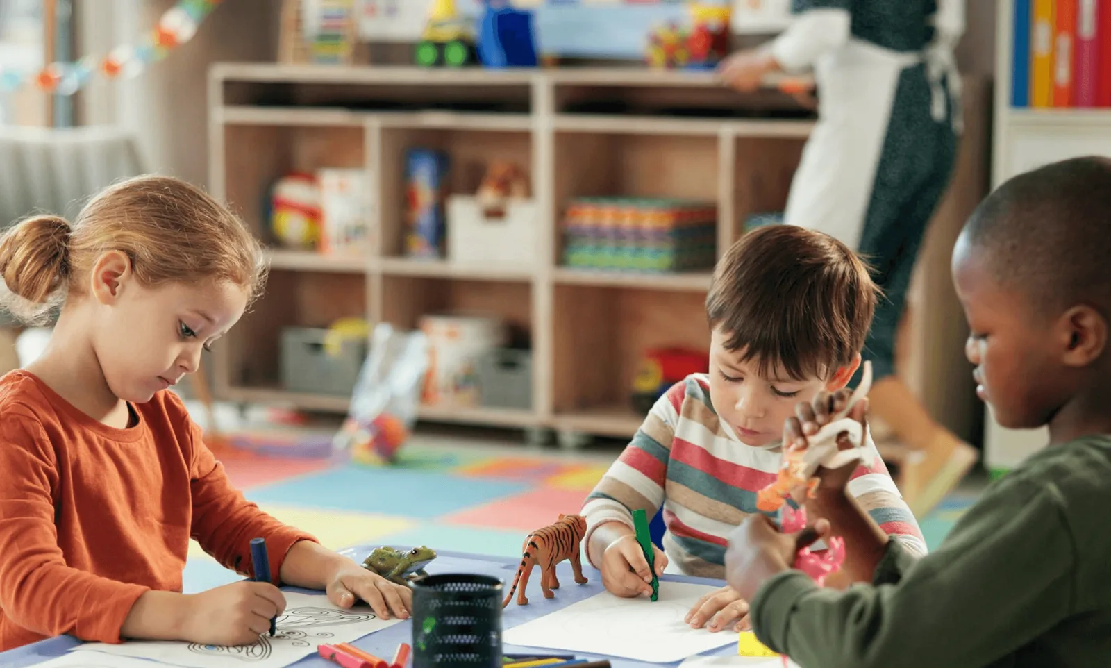 A teacher setting up a classroom with children watching