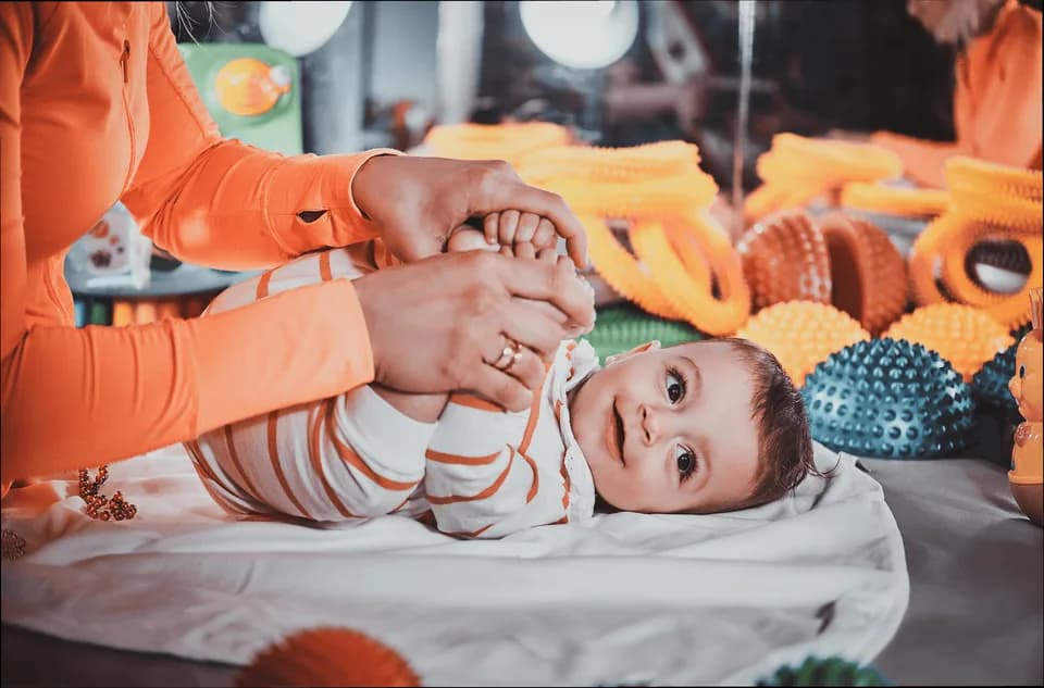 A carer playing with a baby among soft sensory toys